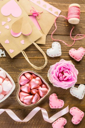 Photo for Pink roses with chocolates on rustic wood table. - Royalty Free Image