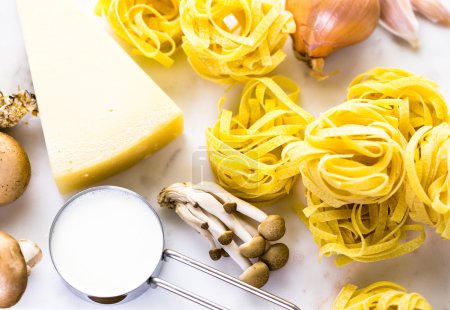 Photo for Ingredients for preparing fettuccine with creamy mushroom sauce on wooden table - Royalty Free Image