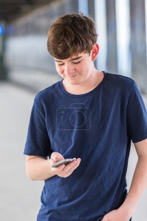 Photo for Teenage boy at the lightrail station with phone in urban area. - Royalty Free Image