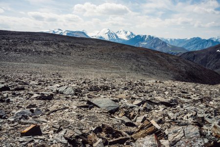 Vue du col pierreux à la grande chaîne de montagnes et le glacier. Neige au sommet d'une crête de montagne géante. Paysage ensoleillé avec de belles grandes montagnes enneigées. Pic enneigé et monts glaciaires sous les nuages.