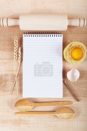 Téléchargez les photos : Ingrédients de cuisson pour la cuisine et cahier de recettes sur une planche en bois
. - en image libre de droit