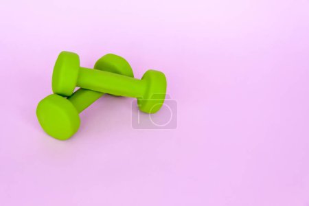 Mancuernas verdes para deportes sobre fondo rosa. Deportes, nutrición deportiva, alimentación saludable, dieta. Espacio para el texto. Ejercicio, bajar de peso.
