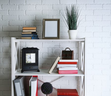 Bookshelves with books and decorative objects on brick wall background