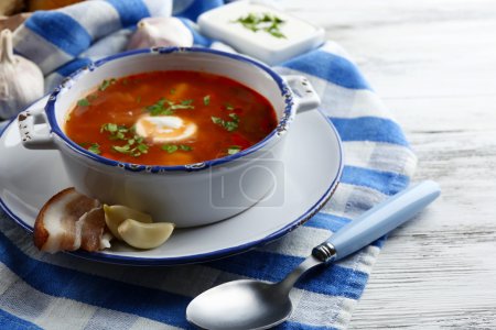 Ukrainian beetroot soup - borscht, on blue napkin, on wooden background