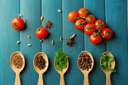 Photo for Tomatoes with wooden spoons with fresh herbs and spices on wooden background - Royalty Free Image