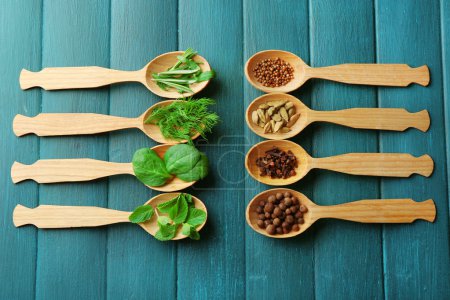 Cucharas de madera con hierbas frescas y especias sobre fondo de madera
