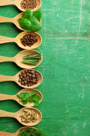 Photo for Wooden spoons with fresh herbs and spices on color wooden background - Royalty Free Image