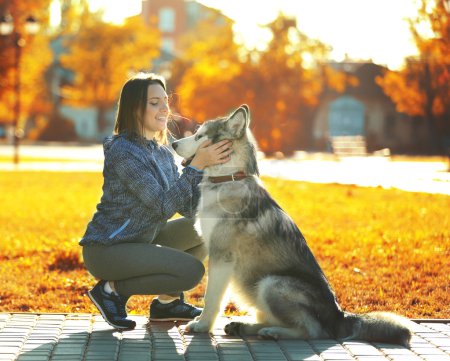 Foto de Feliz joven mujer caminando con su perro en el parque - Imagen libre de derechos