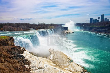 Photo for Niagara Falls from American side and Skyscrapers in Canada. A view on American Falls, Bridal Veil Falls, Goat Island, Horseshoe falls and Canada Skyscrapers on the background. - Royalty Free Image