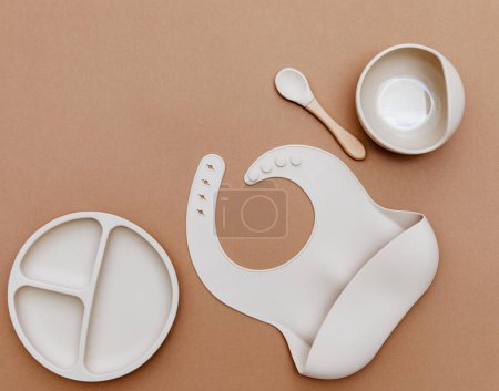 Flat lay beige silicone dishware for baby. Serving kid first feeding concept. copy space, top view