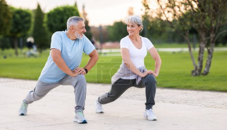 Energiza tu mañana. Longitud completa de activa feliz pareja de ancianos en ropa deportiva que trabajan juntos en el parque de la ciudad por la mañana. Alegre marido y mujer mayores haciendo deporte al aire libre, calentando