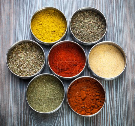 Photo for Various spices and herbs in metal containers on wooden table - Royalty Free Image