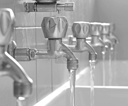 Photo for Many open faucets with water flowing in the bath changing rooms - Royalty Free Image