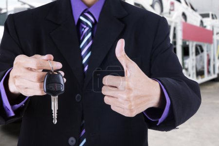 Empresario muestra signo OK y una llave del coche
Empresario muestra signo OK y una llave del coche
