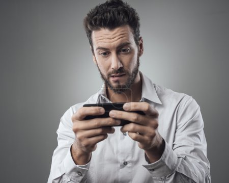 Foto de Joven guapo jugando con su smartphone - Imagen libre de derechos