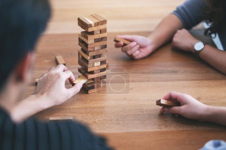 Imagen de cerca de tres amigos sentados y jugando Tumble torre juego de bloques de madera juntos Imagen de cerca de tres amigos sentados y jugando Tumble torre juego de bloques de madera juntos
