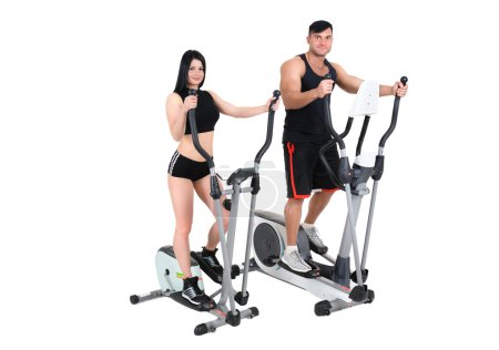 Photo for Young pair of woman and man doing exercises with elliptical trainers together, isolated on white background - Royalty Free Image