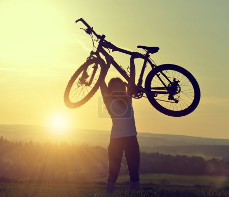 Foto de Chica con bicicleta en la puesta del sol - Imagen libre de derechos