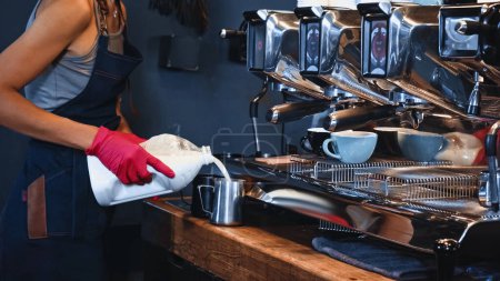 vista recortada de barista vertiendo leche de caja de cartón 