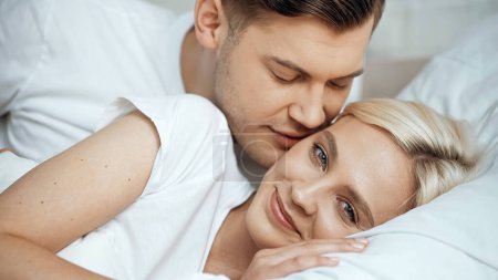 young man kissing cheek of happy blonde girlfriend 