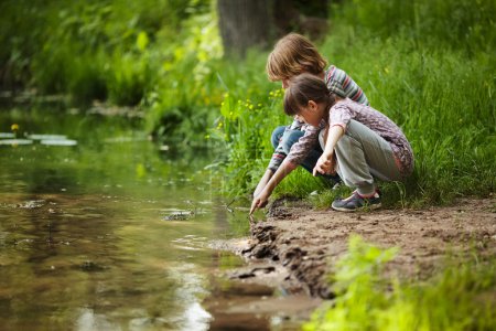 Téléchargez les photos : Garçon avec une fille assise près de l'eau - en image libre de droit