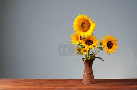 Photo for Sunflower in a ceramic vase on a wooden table - Royalty Free Image