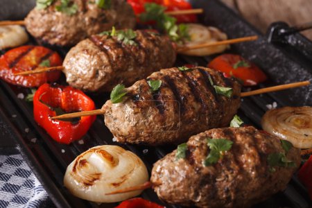 Kofta kebabs with vegetables closeup on a grill pan. horizontal