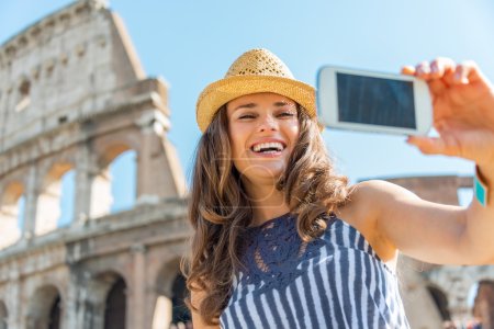 Mujer joven sonriente haciendo selfie delante del coliseo en roma
,