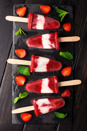 Photo for Homemade strawberry yogurt ice cream popsicles on slate - Royalty Free Image