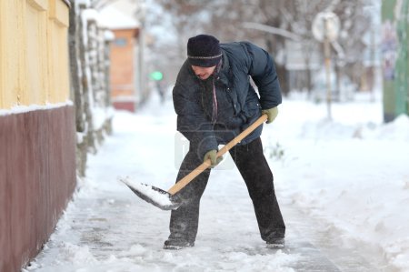 Foto de Mujer caucásica limpiando nieve de la acera con pala - Imagen libre de derechos