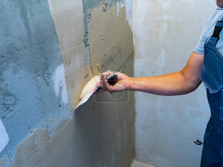 Foto de Mejora de la casa por trabajador. Mano con una espátula. Paletas de trabajo masilla en la pared con acabado masilla - Imagen libre de derechos