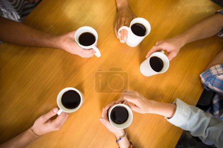 Manos sosteniendo tazas de café en la mesa
Manos sosteniendo tazas de café en la mesa