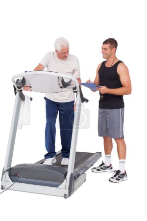 Hombre mayor en cinta de correr con entrenador
Hombre mayor en cinta de correr con entrenador