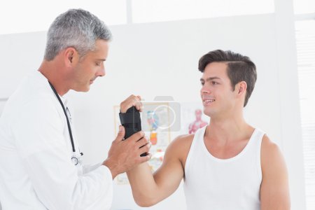 Doctor examinando la muñeca de un hombre
