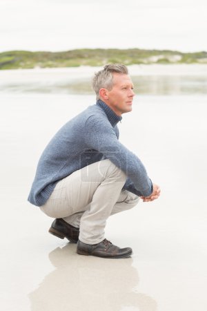 Man crouched down at the shore