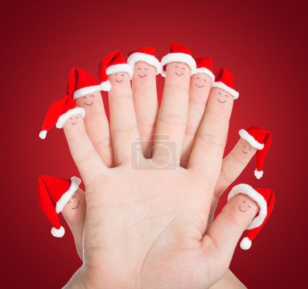 Photo for Fingers faces in Santa hats against red background. Happy friends or family celebrating holiday concept for Christmas or New Years day - Royalty Free Image