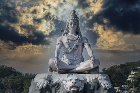 Statue des meditierenden Hindugottes Shiva gegen Himmel und Wolken am Ganges im indischen Dorf Rishikesh, Nahaufnahme