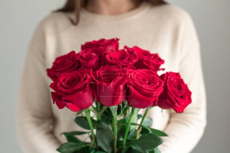 Mujer sosteniendo fresco ramo de flores en flor de rosas rojas. Copiar espacio Mujer sosteniendo fresco ramo de flores en flor de rosas rojas. Copiar espacio