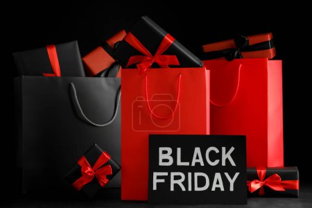 Einkaufstaschen aus Papier und Geschenkboxen auf dunklem Hintergrund. Black-Friday-Verkauf