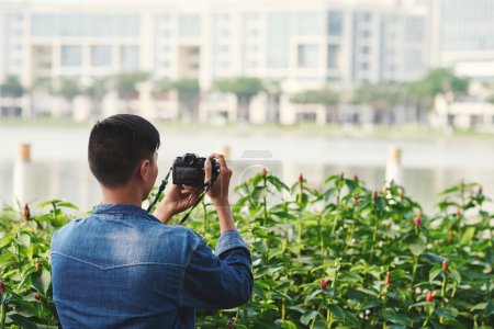 Téléchargez les photos : Touriste prenant des photos dans le parc de la ville, vue de l'arrière - en image libre de droit