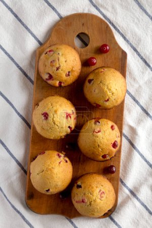 Hausgemachte Cranberry-Muffins mit Orangenschale auf rustikalem Holzbrett auf Stoff, Draufsicht. Flache Lage, über Kopf, von oben.