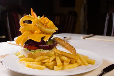 Foto de Hamburguesa con queso gourmet y papas fritas en plato en la mesa en el restaurante - Imagen libre de derechos