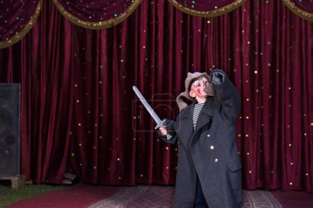 Niño usando traje sosteniendo la espada en el escenario
