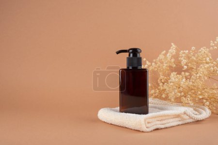 Foto de Mantel ecológico con botella de bomba de ámbar sobre fondo beige con plantas secas. Cuidado de la piel concepto cosmético natural para el cuidado del cuerpo de la cara - Imagen libre de derechos