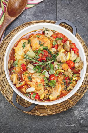 Foto de Plato de pollo estofado en salsa de tomate con vino, verduras y especias, listo para comer. Enfoque selectivo - Imagen libre de derechos