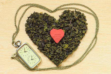 Té verde deja en forma de corazón y reloj
