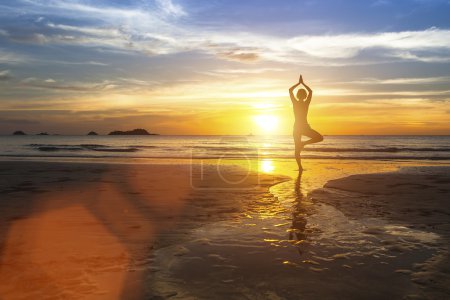 Photo for Silhouette of woman standing at yoga pose on the beach during amazing sunset. - Royalty Free Image