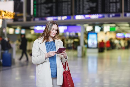 Mujer joven en el aeropuerto internacional, control de tablero electrónico
