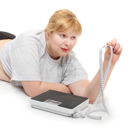 Photo for Overweight woman with measure tape and weighing machine. Healthy lifestyle theme. Obesity and other civilization illness. - Royalty Free Image