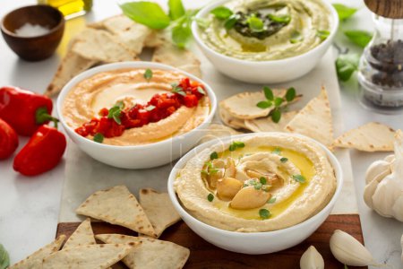 Photo for Hummus board with garlic, roasted red pepper and basil variety, served with pita - Royalty Free Image